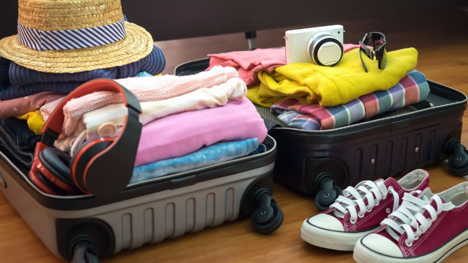 Ein Koffer voller Kleidung, Schuhe und Zubehör, bereit für eine Reise.