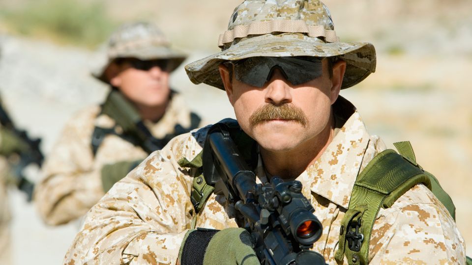 Ein Soldat in Tarnuniform mit Gewehr, fokussiert und bereit.