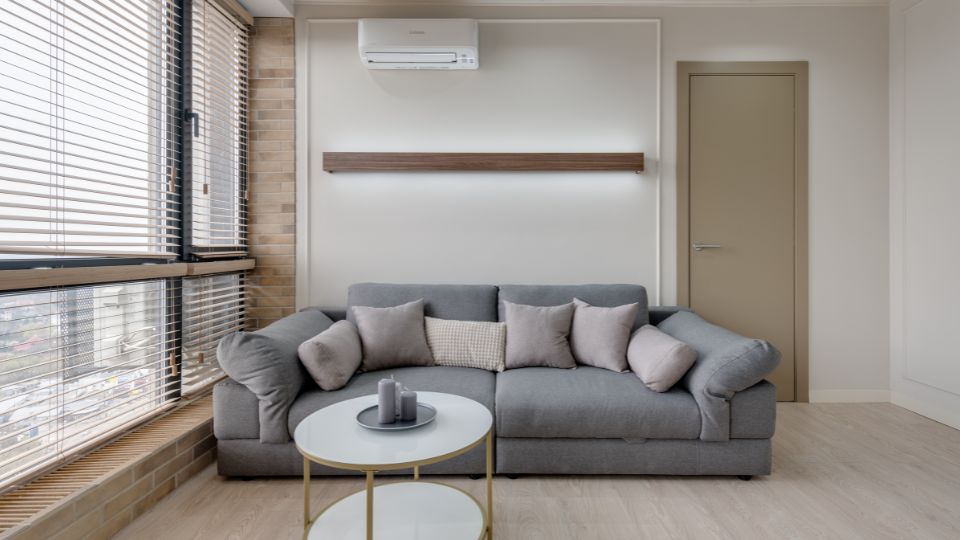 Ein modernes, graues Sofa mit Kissen in einem hellen Raum.